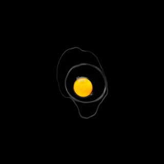 An egg yolk centered in nested black dishes