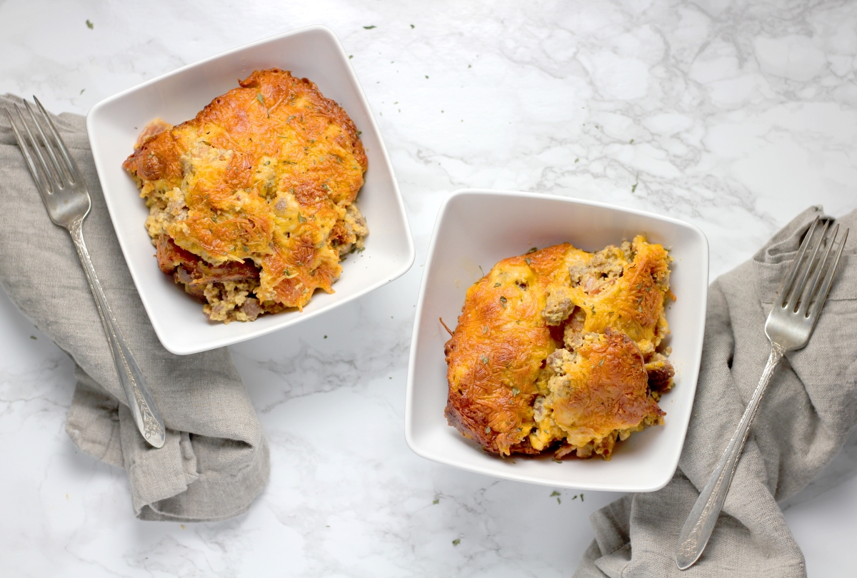 two plates of bacon cheeseburger casserole next two each other with a fork beside each dish 