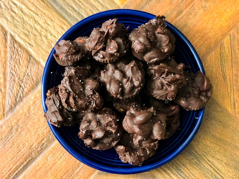 close up top view of chocolate covered peanut clusters served on a plate 