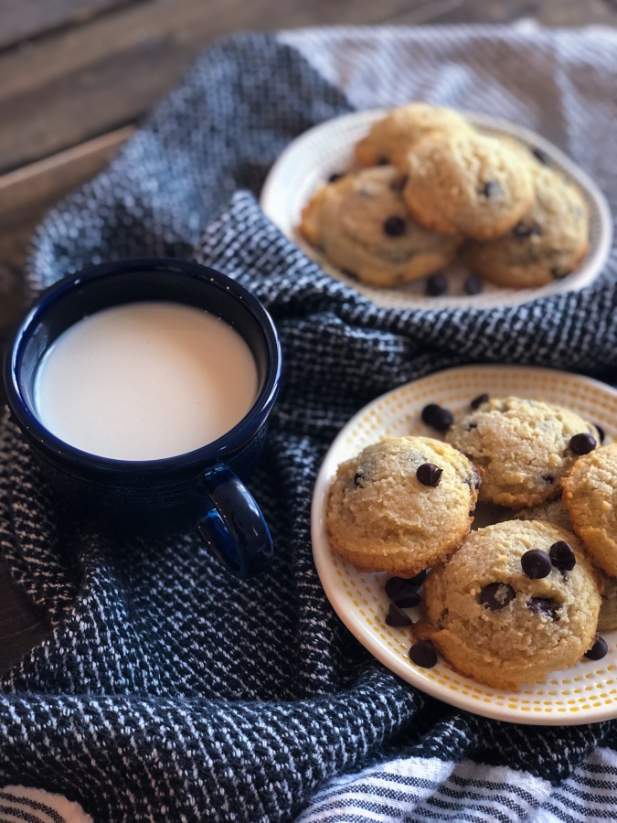 Two plates of keto chocolate chip cookies with a glass of milk in between