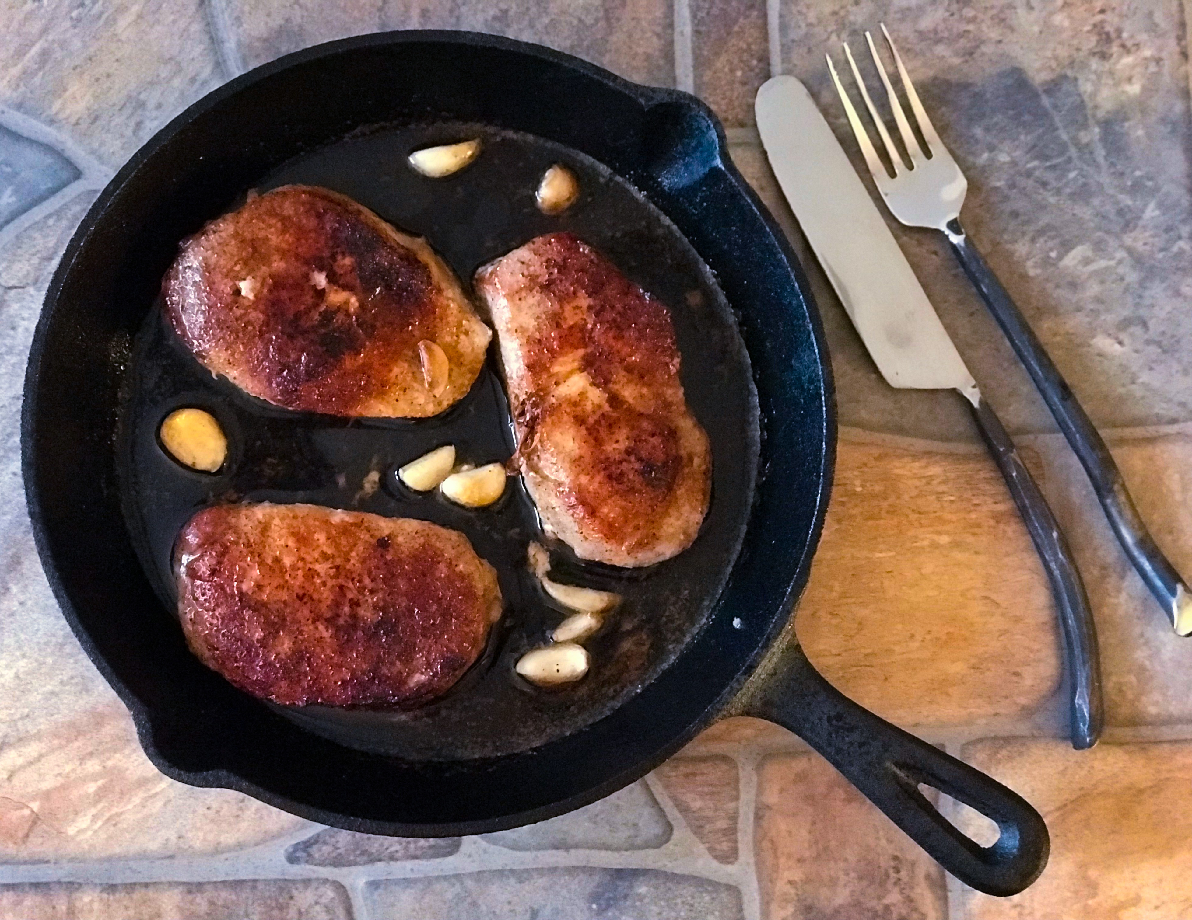 top view of garlic pork chops in a skillet pan