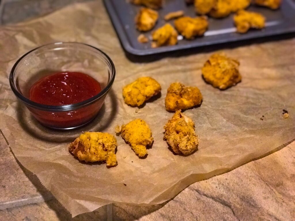 spicy popcorn chicken bites next to a small bowl with ketchup
