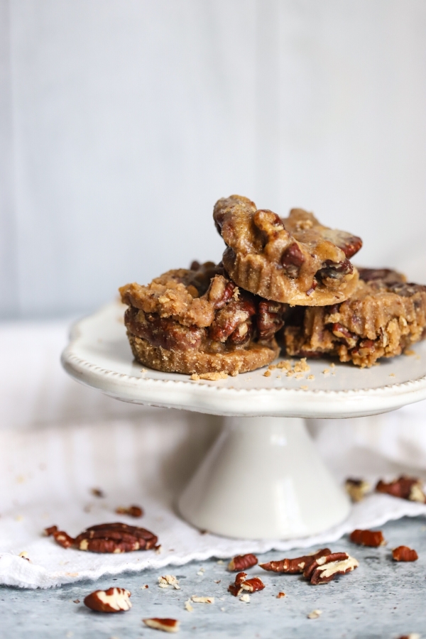 three pecan pralines on top of a mini cake stand with crushed pecan on the bottom