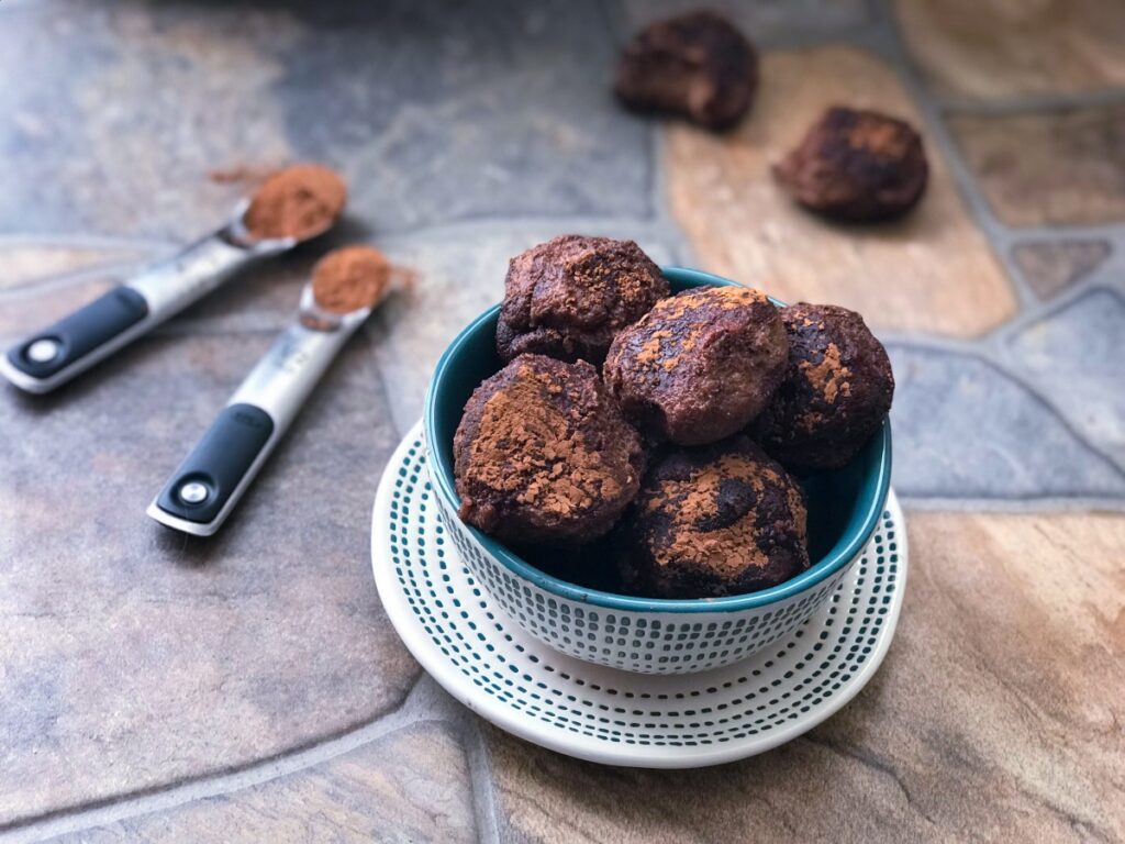 bowl of cocoa peanut butter truffles with two in the background