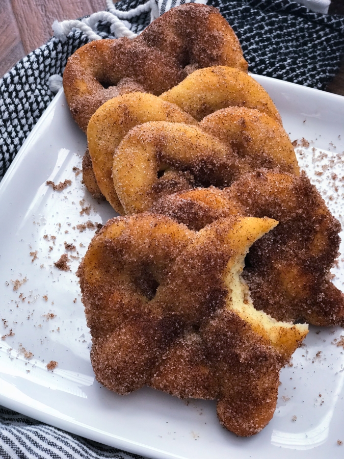 cinnamon sugar pretzels lined up together on a plate with one bitten into