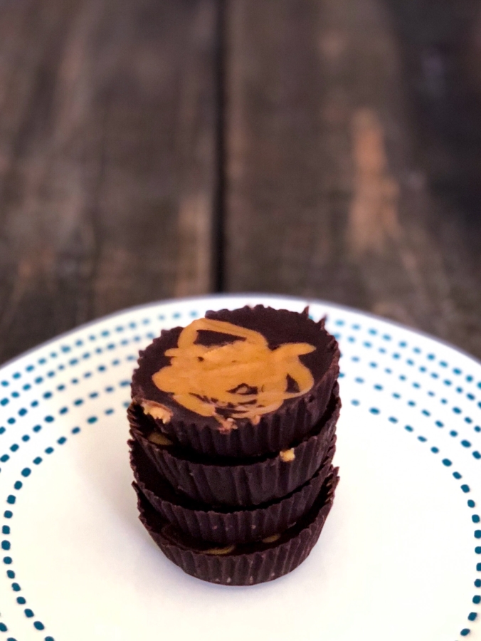 4 keto peanut butter fat bombs stacked up on top of each other on a plate