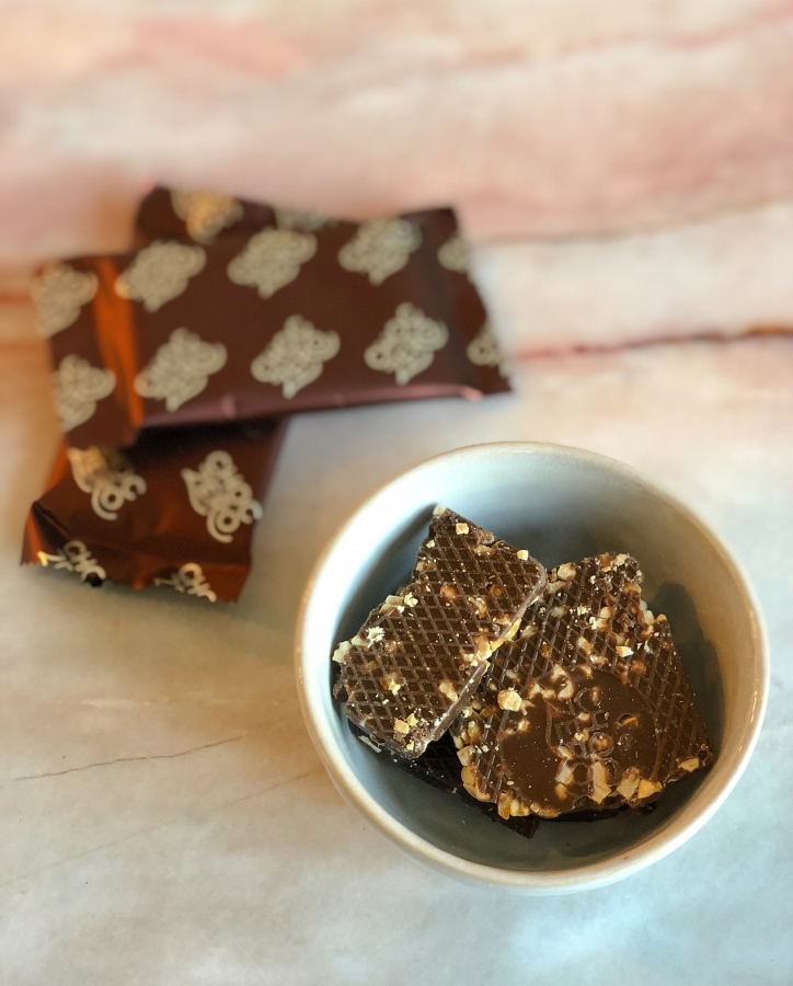a bowl of Choczero chocolate before being melted for strawberries with two packages of the Choczero chocolate bars next to it