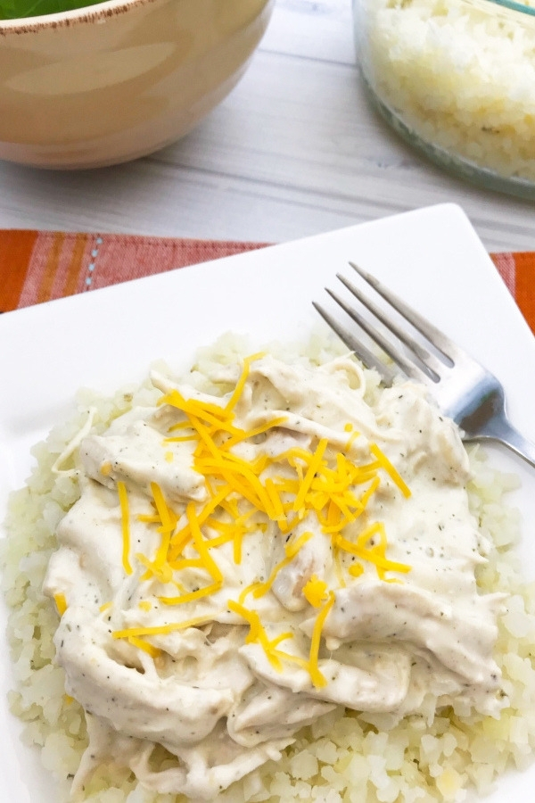 close up photo of cheesy ranch chicken on top of cauliflower rice in a dish