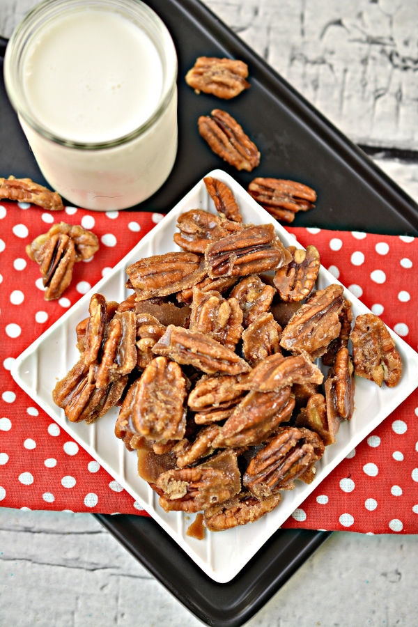 Top view plate of keto candied pecans next to a tall glass of milk