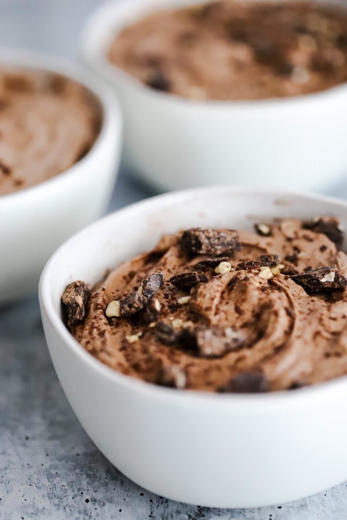 close up of chocolate keto pudding with two blurred in the background