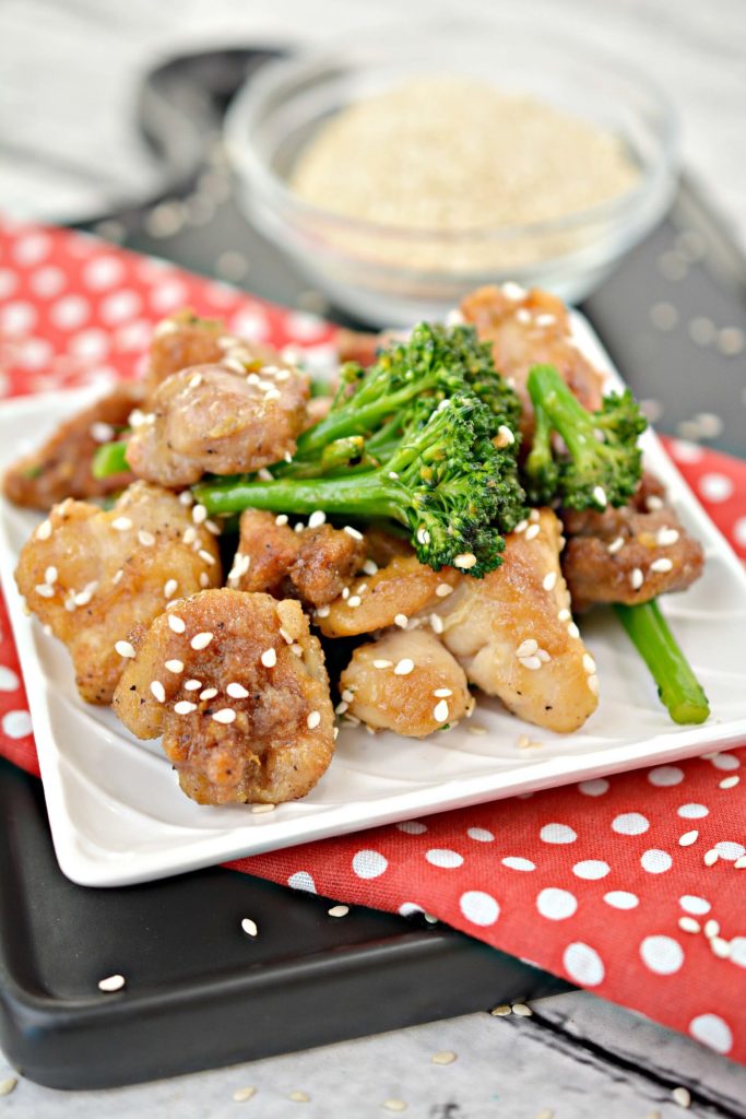 upclose vertical view of keto sesame chicken on a plate with broccoli