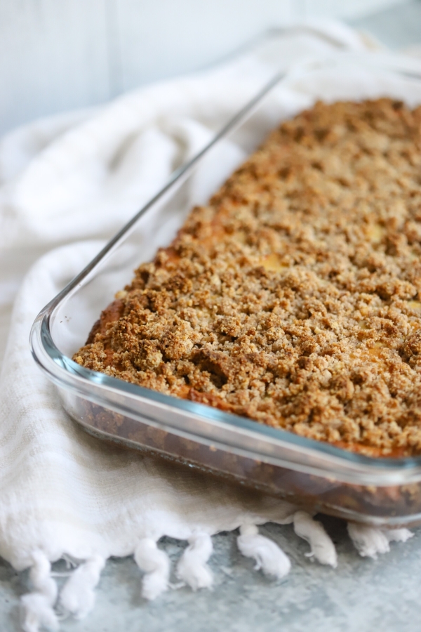 coffee cake fresh out the oven in a small baking glass dish. up close view of the cinnamon crumble