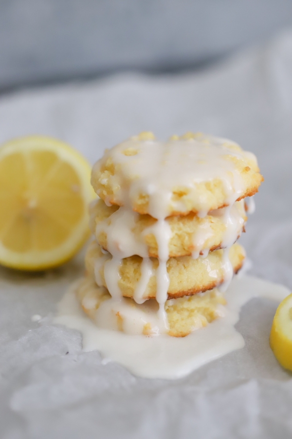 keto lemon cookies stack up on top of each other with glaze dripping down each cookie