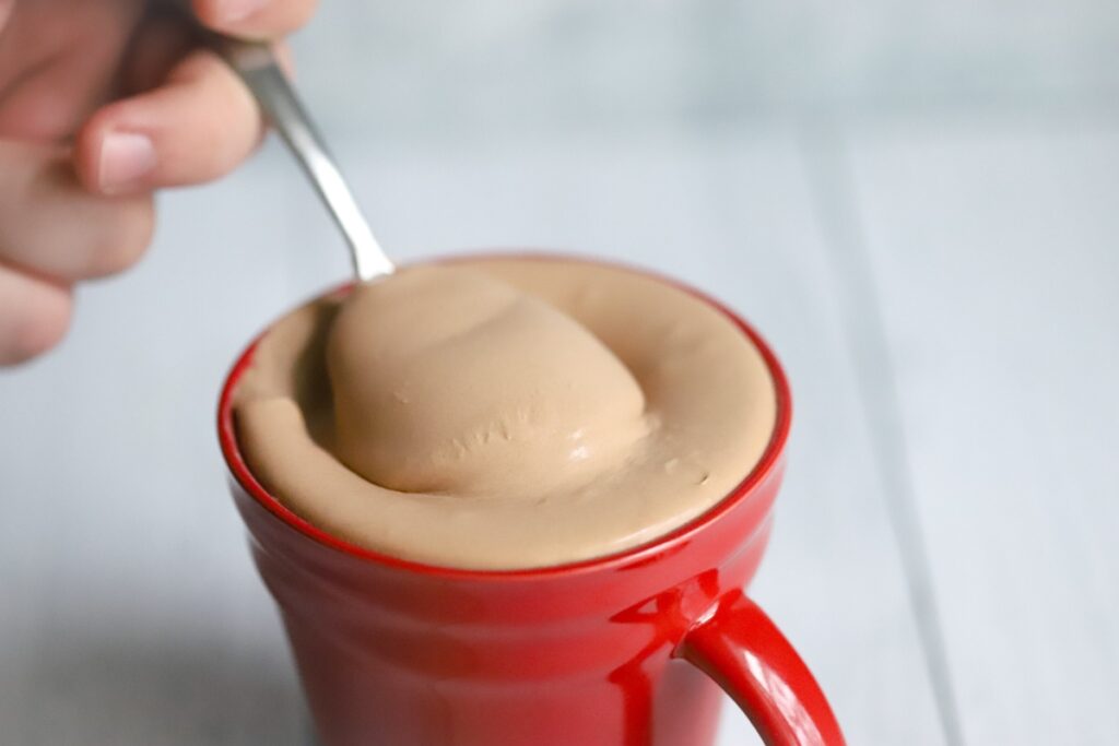 spoonful of keto chocolate frosty being slightly lifted out of the mug