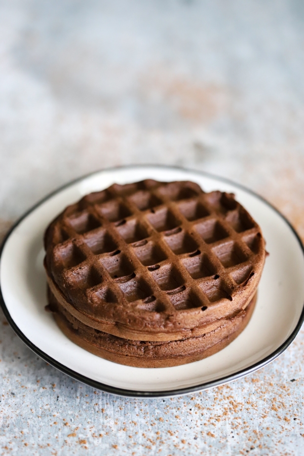two plain chocolate chaffles with no peanut butter filling sitting centered on a plate