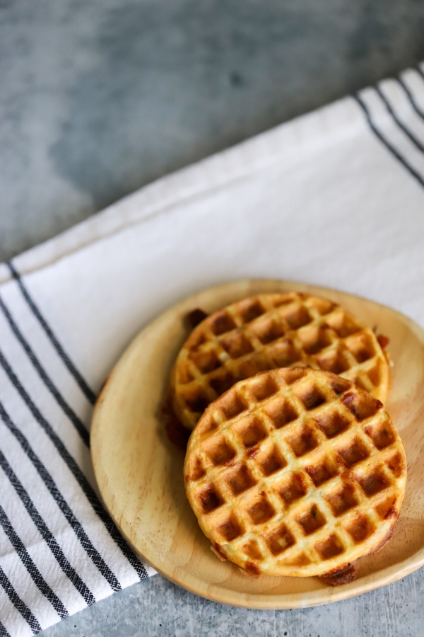 two plain chaffles beside each other on a plate with a napkin underneath