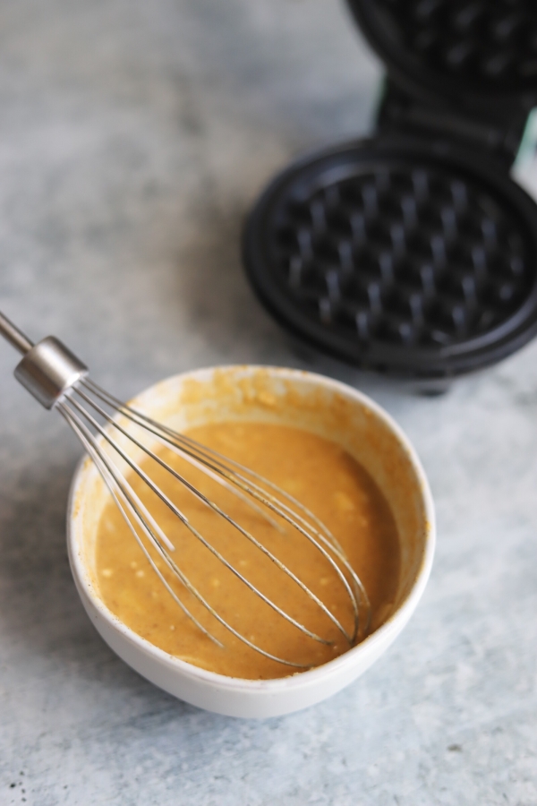 pumpkin chaffle batter in a bowl with a whisk in it