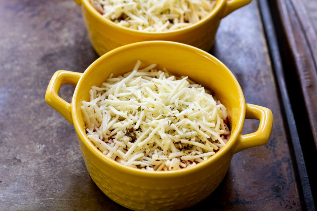 lasagna bowls topped with shredded cheese ready to go in the oven