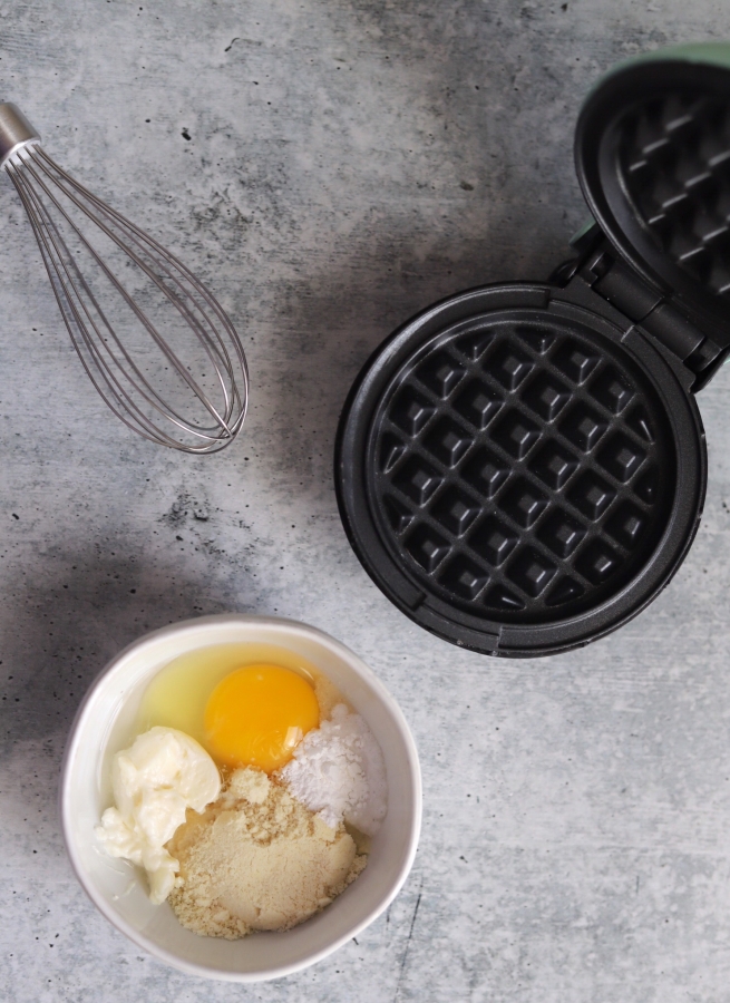a bowl with batter and the mini waffle maker in the background