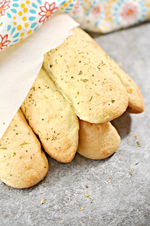 close up of breadsticks bundled together in parchment paper and decorative cloth
