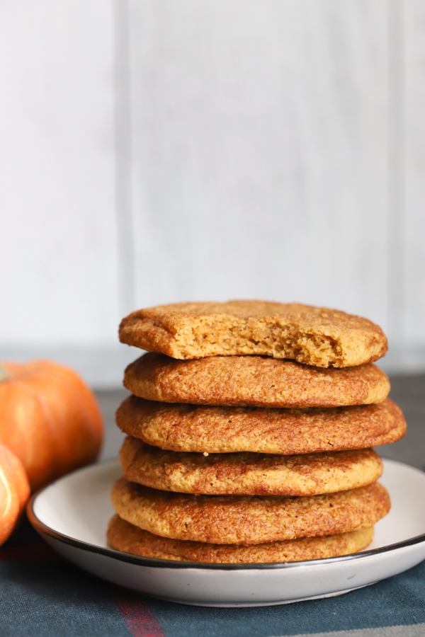 a stack of keto pumpkin snickerdoodle cookies that have a bite taken out of the first one on top