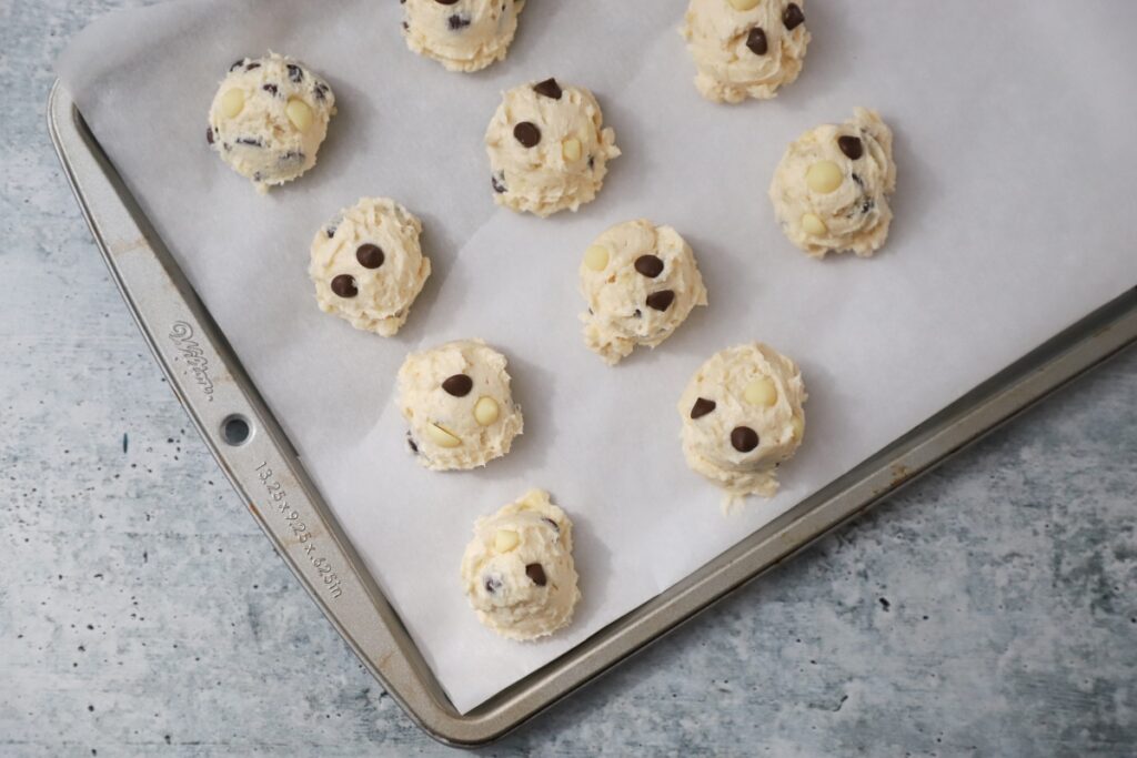 scooped cookie dough a parchment paper lined baking pan