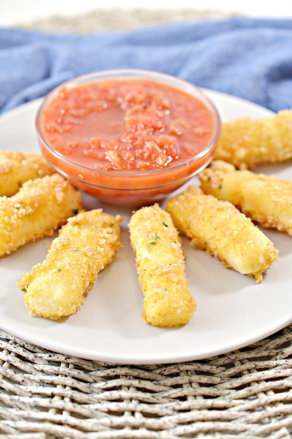 a plate of keto mozzarella cheese sticks with a bowl of marinara sauce in the middle