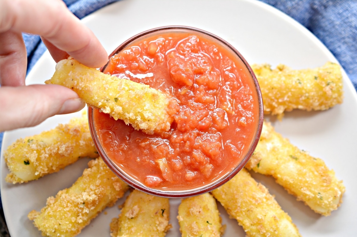 cheese stick being dipped into marinara sauce