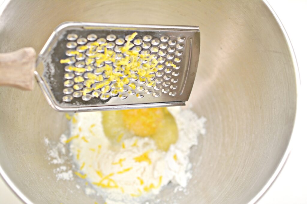 grated lemon being added into a mixing bowl