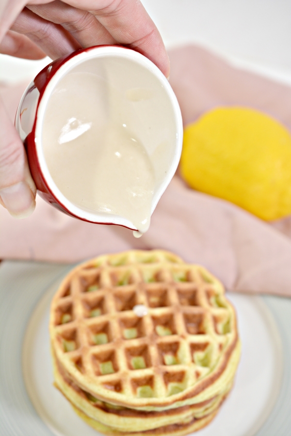 lemon glaze being poured on top of a stack of lemon chaffles