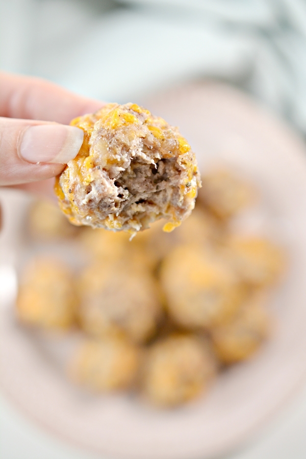 holding up one keto sausage ball with bite taken out of it