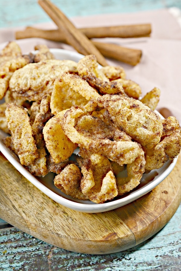 cinnamon sugar pork rinds in a bowl with cinnamon sticks in the background