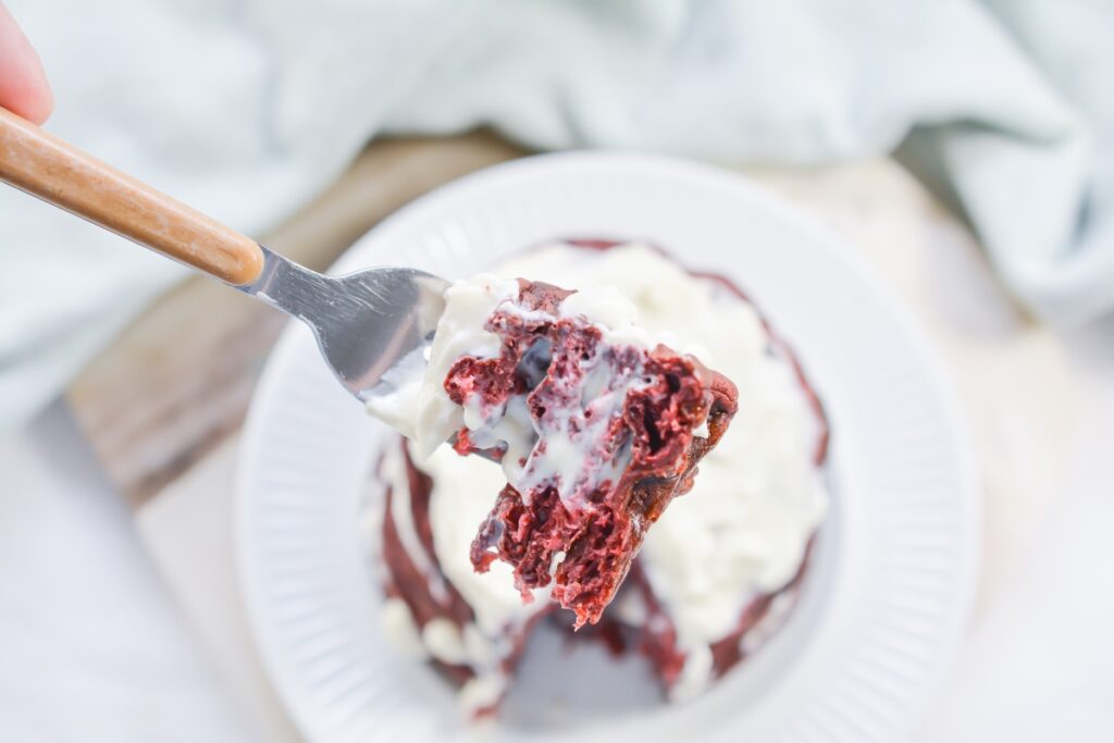 a bite of keto red velvet chaffle on a fork over the plate of chaffles