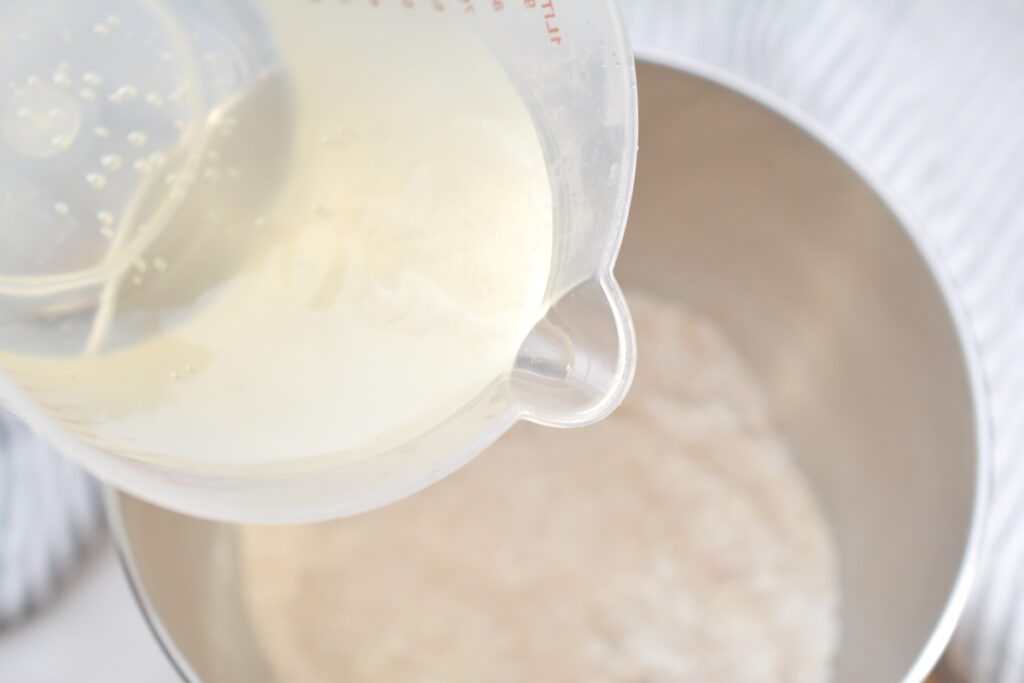 water mixture being poured into the flour bowl mixture