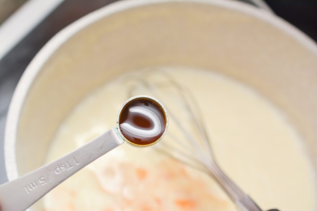 teaspoon of vanilla extract going into saucepan