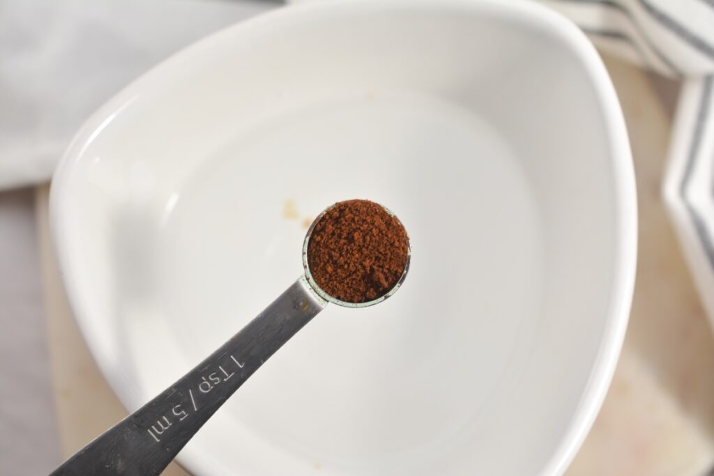 instant coffee powder in a tabespoon over a bowl with water