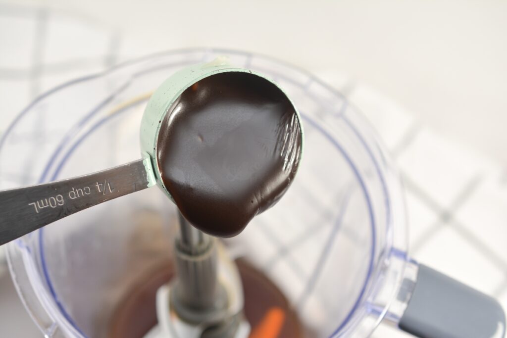 choczero chocolate syrup in measuring spoon being poured into a bowl