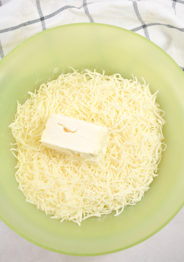 shredded cheese and cream cheese in microwavable bowl