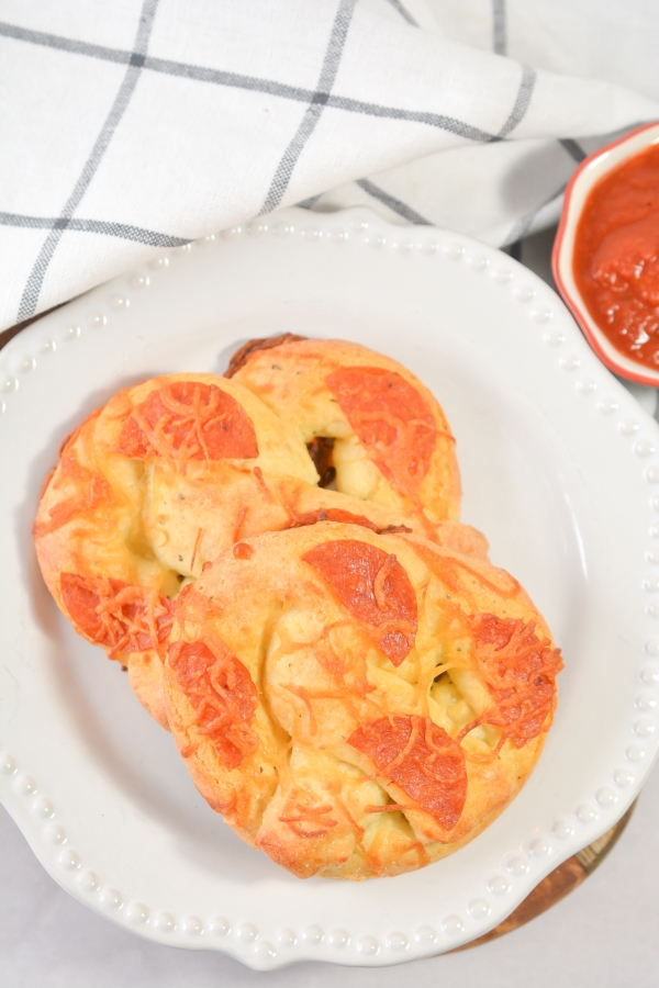 top view of two keto pepperoni pizza pretzels with dipping sauce on the side