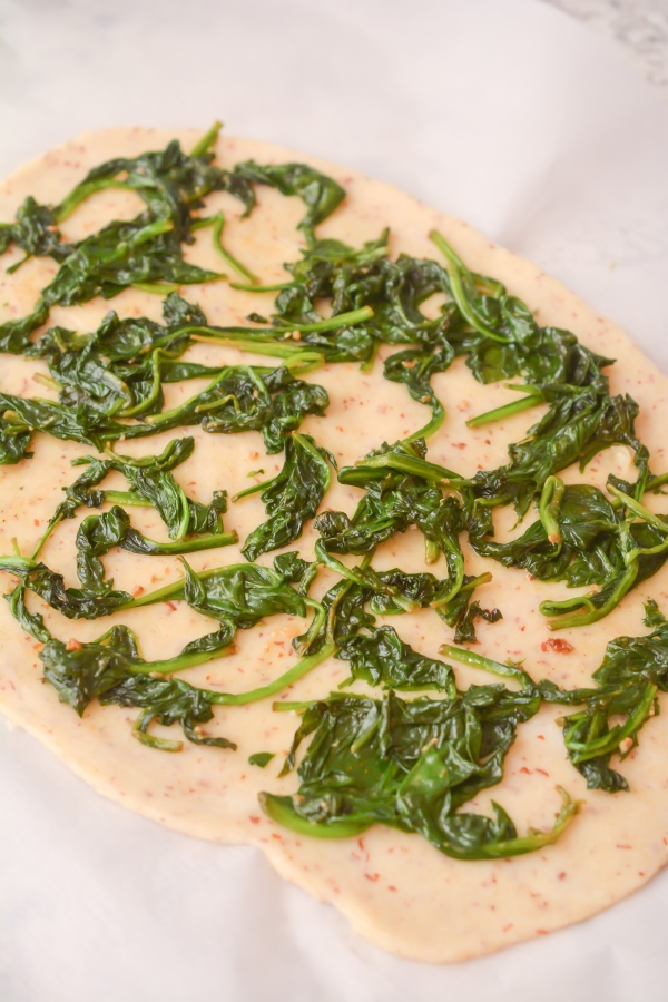 spinach being spread onto dough