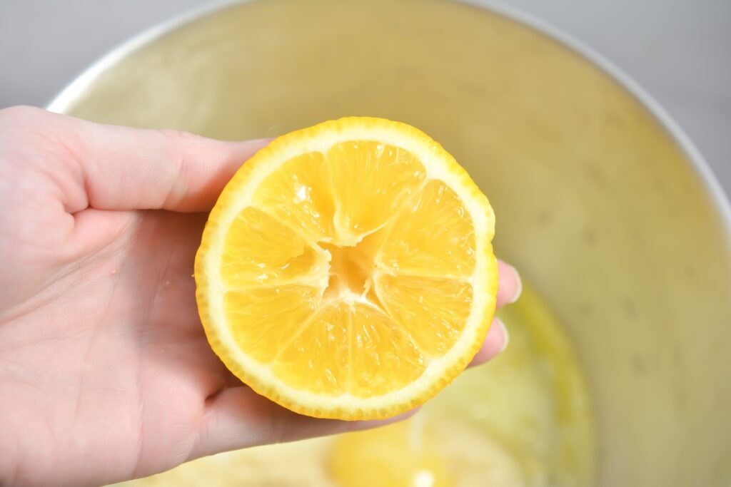 holding half a lemon over a mixing bowl