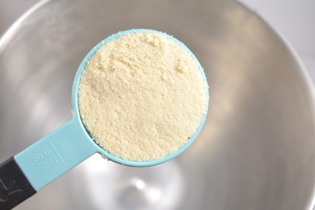 almond flour in a measuring spoon over a mixing bowl